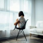 Mujer mirando por la ventana con expresión melancólica, simbolizando el dolor invisible en el autismo.