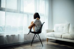 Mujer mirando por la ventana con expresión melancólica, simbolizando el dolor invisible en el autismo.