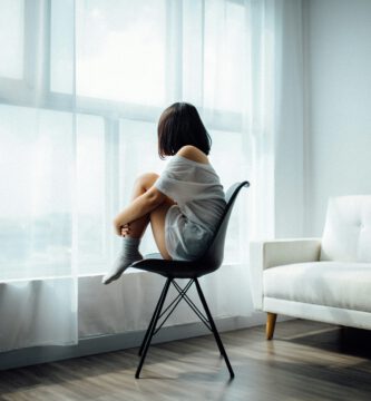 Mujer mirando por la ventana con expresión melancólica, simbolizando el dolor invisible en el autismo.