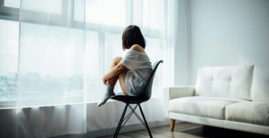 Mujer mirando por la ventana con expresión melancólica, simbolizando el dolor invisible en el autismo.
